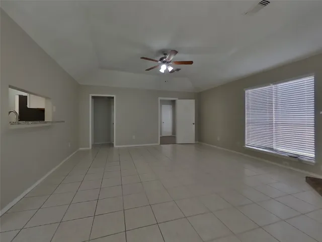 a view of an empty room with a ceiling fan and a window