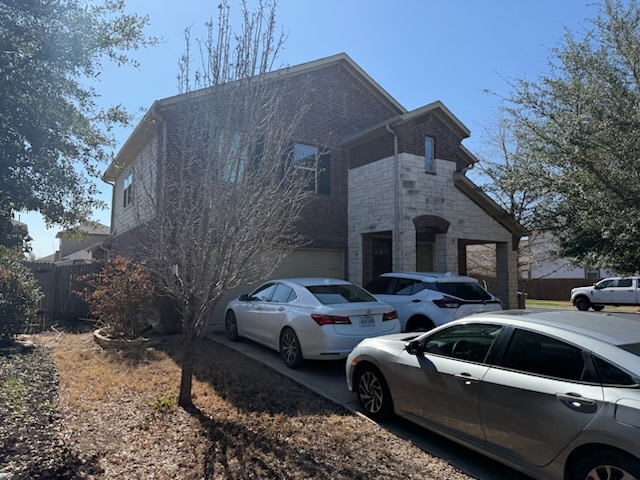 View of front of home featuring brick siding, a garage, and driveway