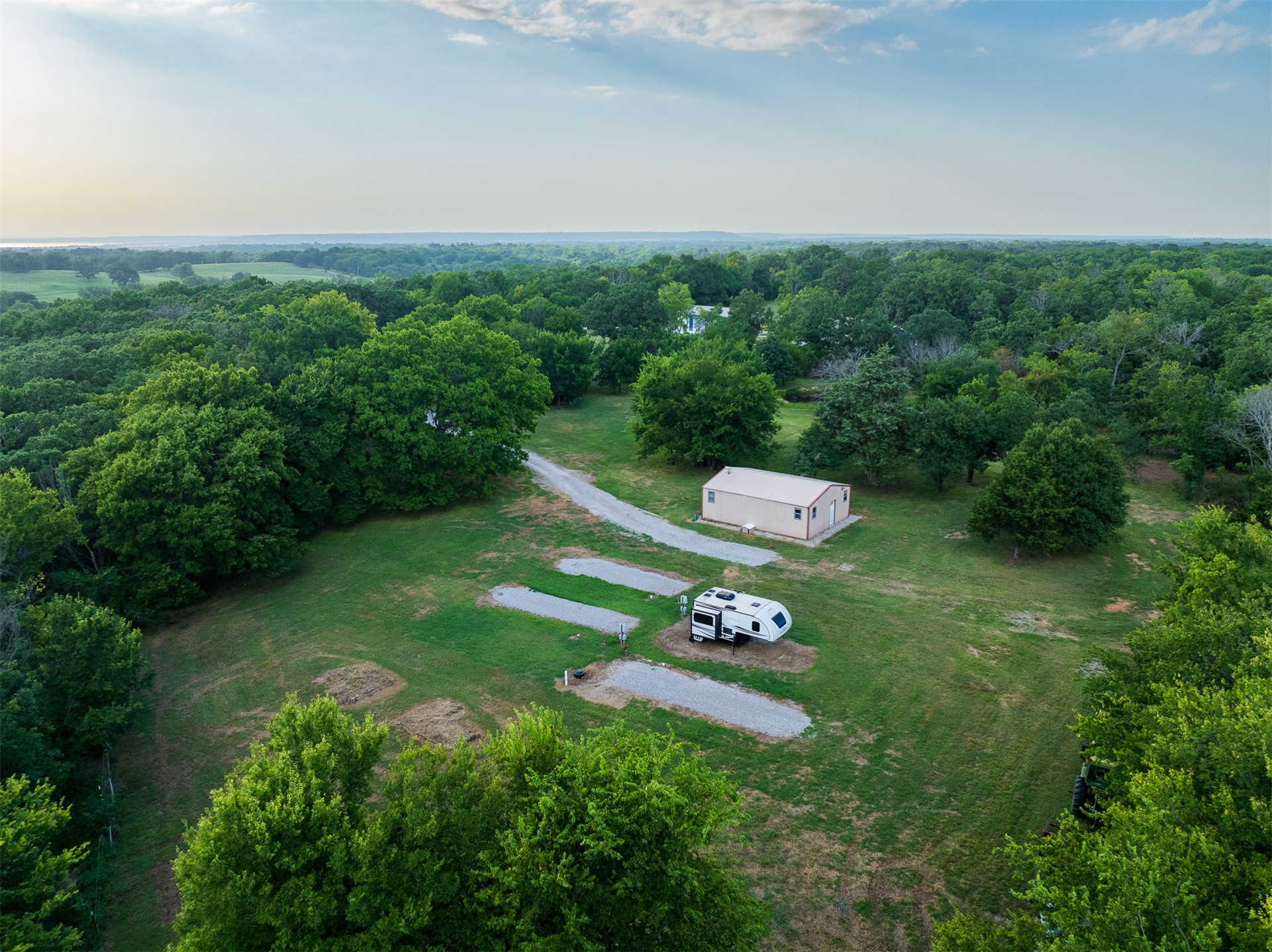 15291 East 400 Road Claremore, OK 74017 - Photo 64 of 96 Expansive wooded property featuring a metal outbuilding, gravel drives, and multiple gravel pads