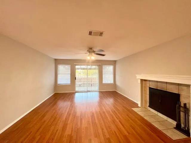an empty room with wooden floor fireplace and windows