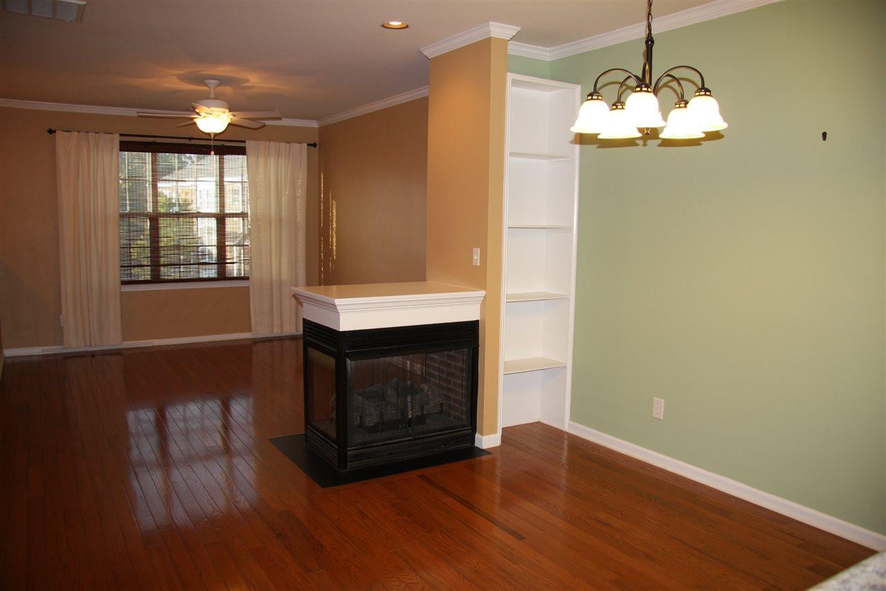 1045 Summerhouse Road Cary, NC 27519 - Photo 3 of 20 a room with wooden floor a fireplace and a chandelier