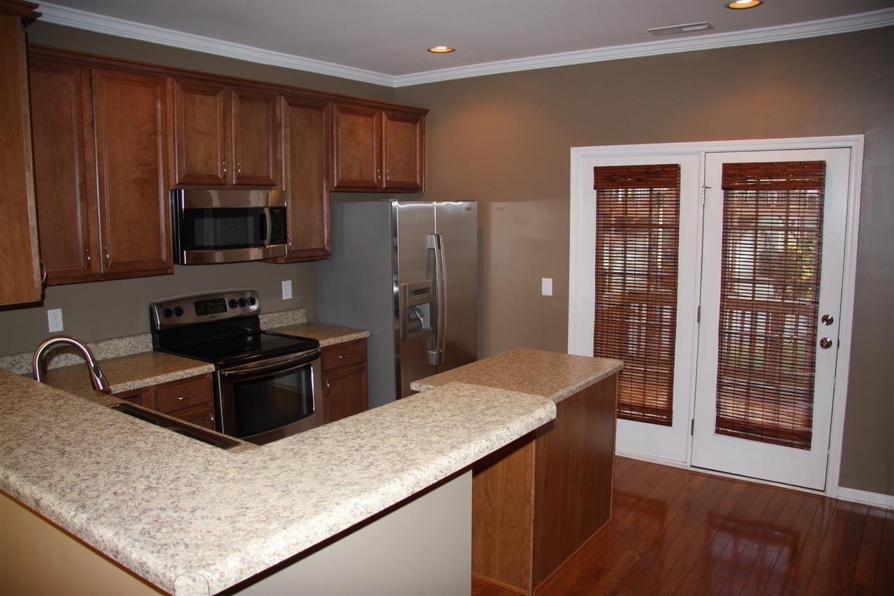 1045 Summerhouse Road Cary, NC 27519 - Photo 5 of 20 a kitchen with kitchen island granite countertop wooden cabinets a refrigerator and a sink