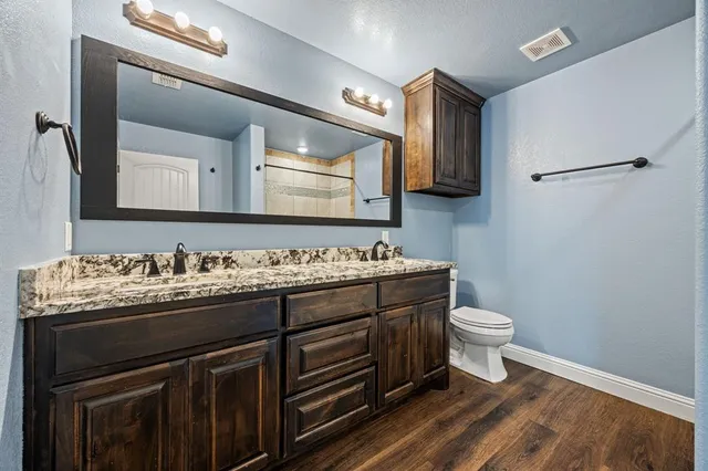 a bathroom with a granite countertop toilet sink and mirror