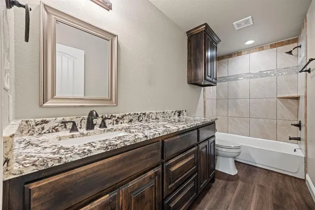 a bathroom with a granite countertop sink a toilet and bathtub
