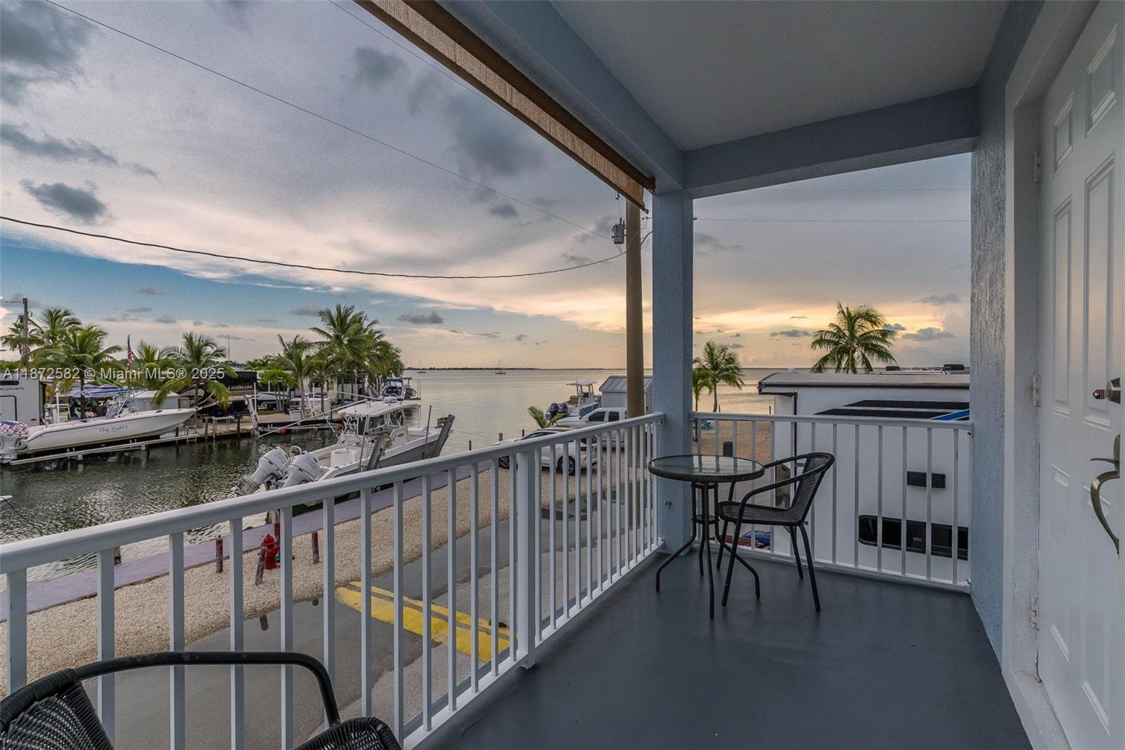 325 Calusa Street, Unit 320 Key Largo, FL 33037 - Photo 16 of 52 a view of a balcony with table and chairs and wooden floor