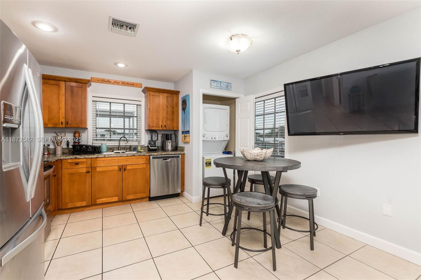 325 Calusa Street, Unit 320 Key Largo, FL 33037 - Photo 22 of 52 a kitchen with granite countertop a stove a sink dishwasher a dining table and chairs with wooden floor