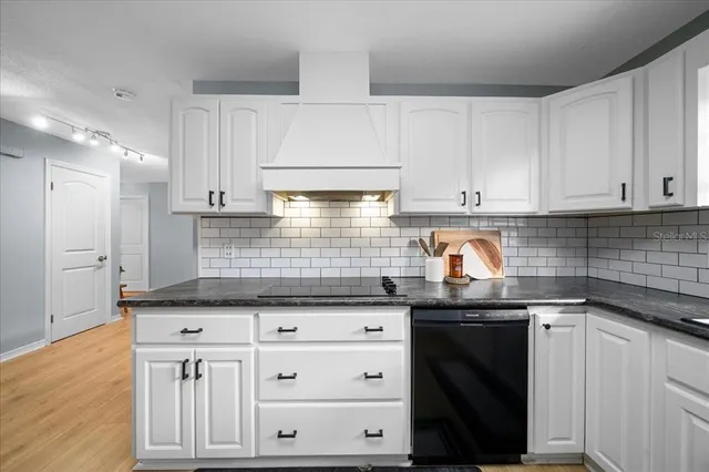 a kitchen with granite countertop a sink a stove and cabinets