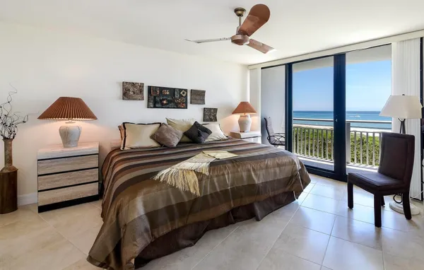 a bedroom with a bed a chair and a large window