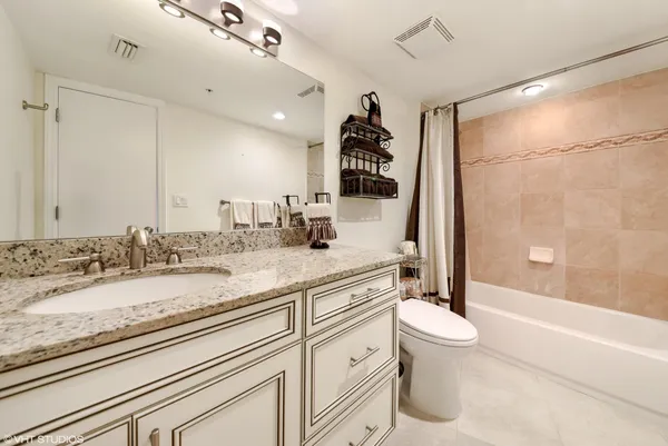 a bathroom with a granite countertop sink mirror vanity and toilet