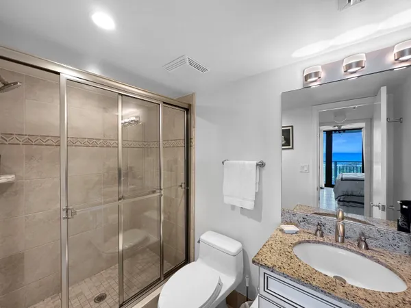 a bathroom with a granite countertop sink toilet a mirror and shower