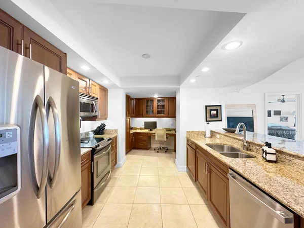 a large kitchen with stainless steel appliances granite countertop a refrigerator and a sink