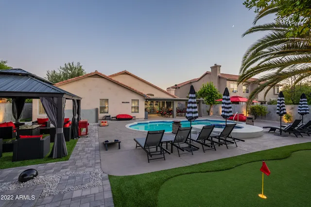a front view of a house with swimming pool table and chairs