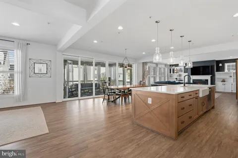 a kitchen with stainless steel appliances kitchen island a table chairs and a refrigerator