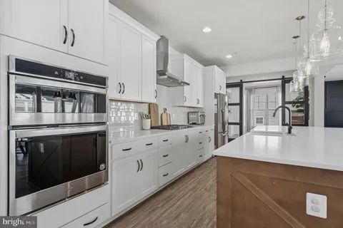 a kitchen with stainless steel appliances granite countertop a center island stools and a refrigerator