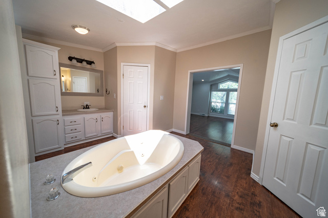 1407 North 1250th Street West Helper, UT 84526 - Photo 19 of 27 Full Master Bathroom featuring a skylight, a jetted tub, crown molding, vanity, and dark wood-style floors