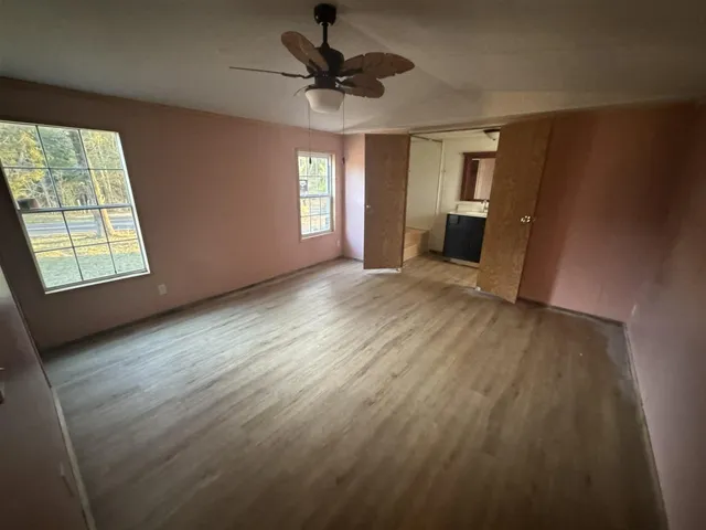 a view of an empty room with a window and wooden floor