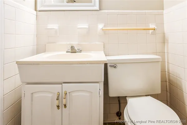 a bathroom with a toilet a sink and wooden floor