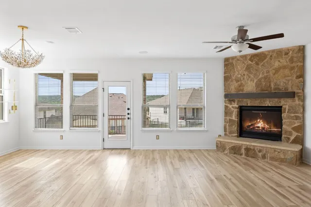 a view of an empty room with wooden floor fireplace and a window