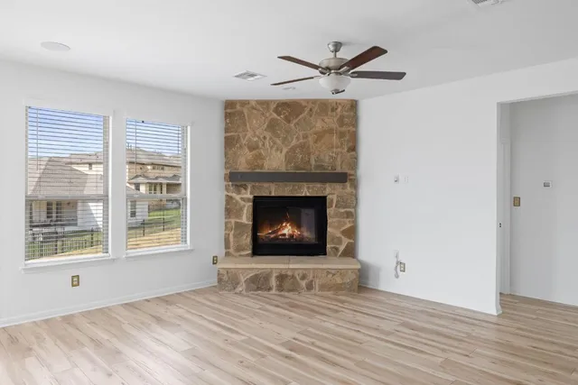 a view of an empty room with wooden floor fireplace and a window