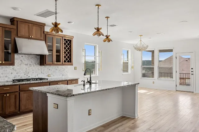 a kitchen with stainless steel appliances granite countertop a sink a stove counter space and wooden floor