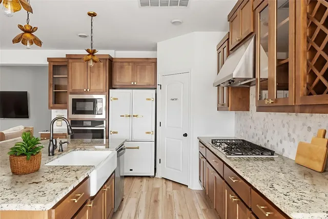 a kitchen with stainless steel appliances granite countertop a stove a refrigerator a sink dishwasher and wooden cabinets with wooden floor