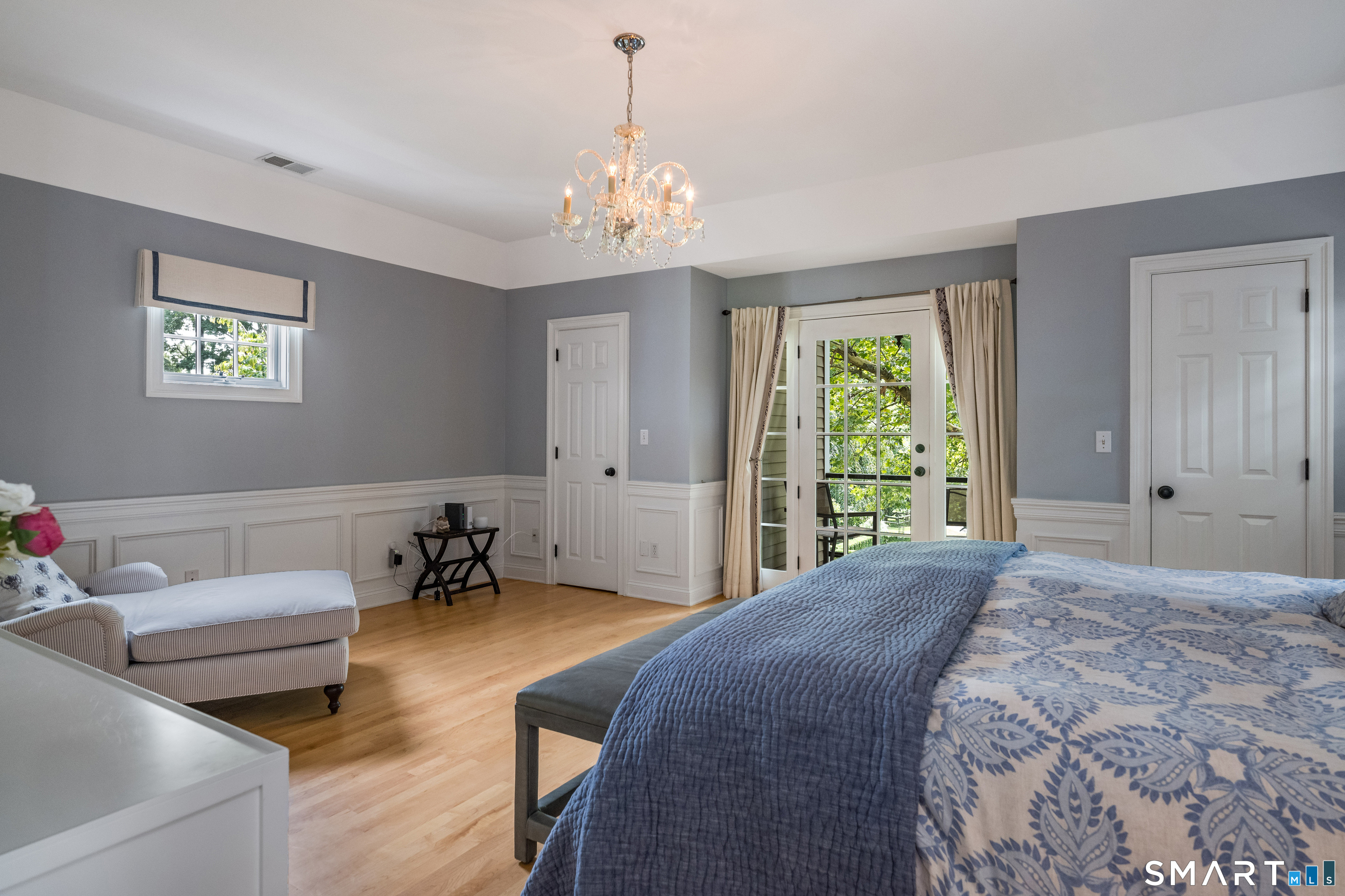 63 Broad Street Guilford, CT 06437 - Photo 20 of 40 a spacious bedroom with a bed a couch and a chandelier