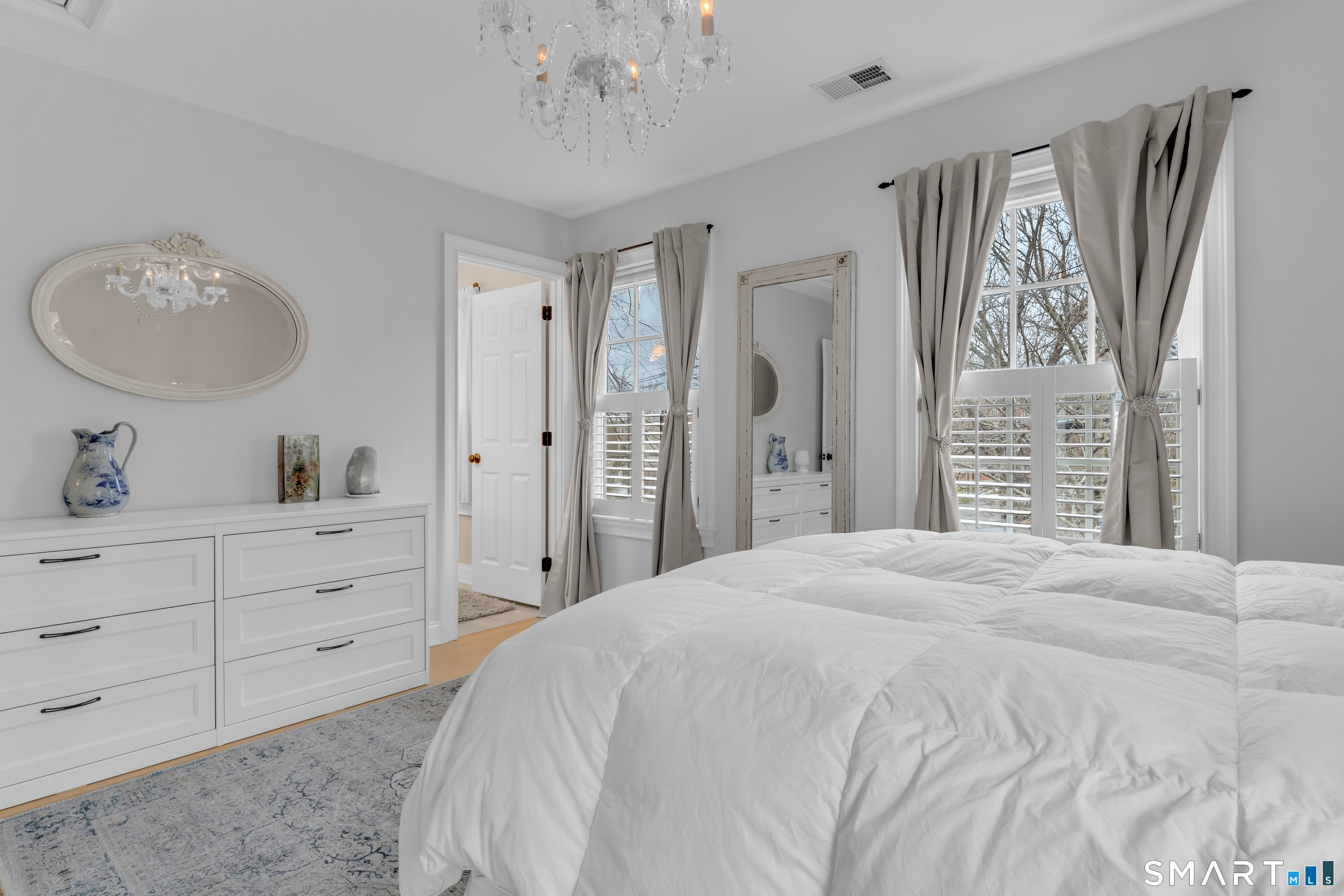 63 Broad Street Guilford, CT 06437 - Photo 24 of 40 a spacious bedroom with a bed and a chandelier