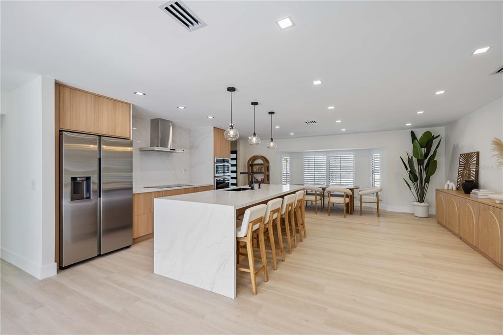 105 Sinclair Street Southeast Port Charlotte, FL 33952 - Photo 15 of 69 a kitchen with stainless steel appliances granite countertop a refrigerator oven a sink a dining table and chairs with wooden floor