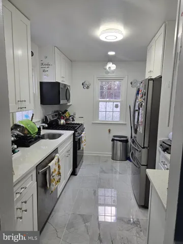 a kitchen with stainless steel appliances a stove a sink a microwave a refrigerator and cabinets