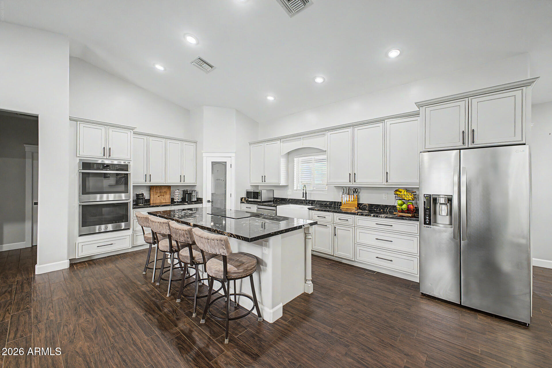 1427 East Whiteley Street Apache Junction, AZ 85119 - Photo 12 of 59 a kitchen with stainless steel appliances a stove a sink a refrigerator and white cabinets with wooden floor