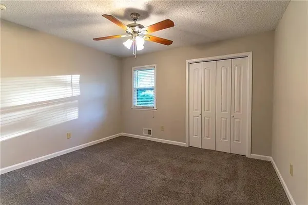 an empty room with windows and fan