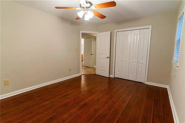 a view of an empty room with wooden floor and a ceiling fan