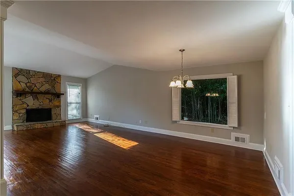 a view of an empty room with wooden floor fireplace and a window