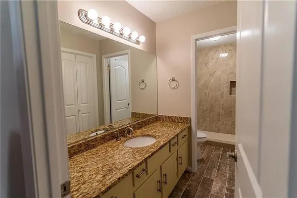 a bathroom with a granite countertop sink a mirror and a shower