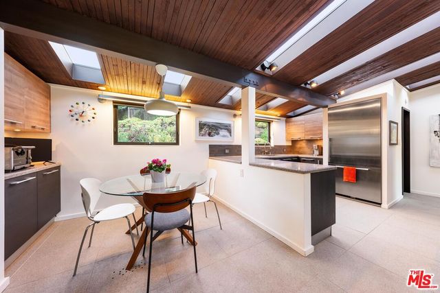 a kitchen with stainless steel appliances kitchen island granite countertop a table chairs and a refrigerator