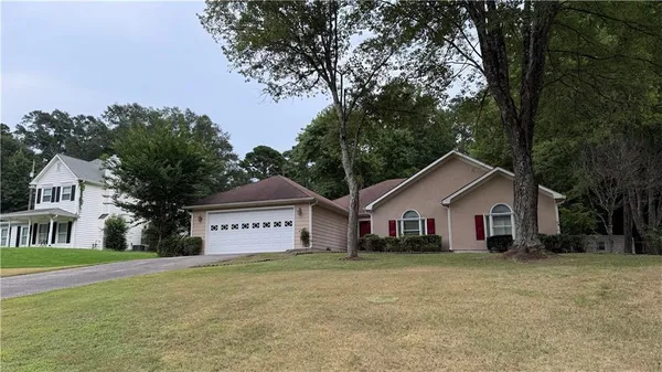 a view of a house with a yard and large tree