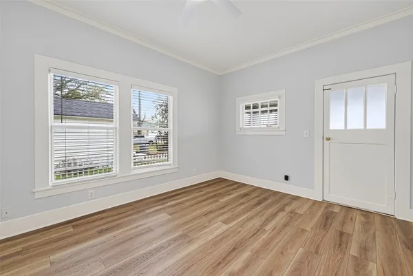 a view of an empty room with wooden floor and a window