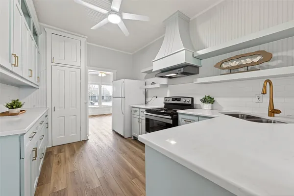 a kitchen with stove a refrigerator and a sink with wooden floor