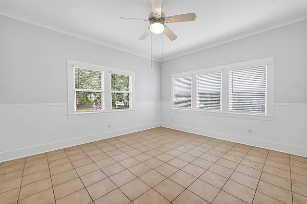 a view of an empty room with a window and chandelier fan