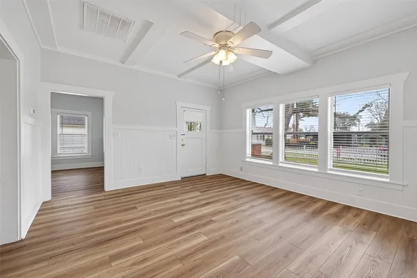 a view of an empty room with wooden floor and a window
