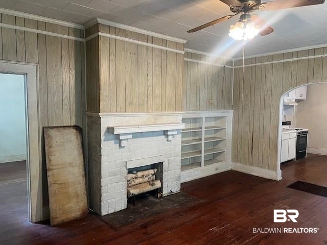 321 Grant Street Chickasaw, AL 36611 - Photo 5 of 13 Unfurnished living room with a ceiling fan, arched walkways, wood walls, a fireplace, and dark wood-style flooring