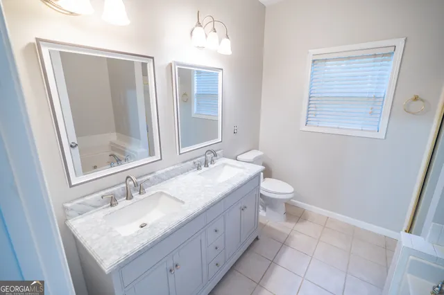 a bathroom with a granite countertop sink a toilet and a mirror