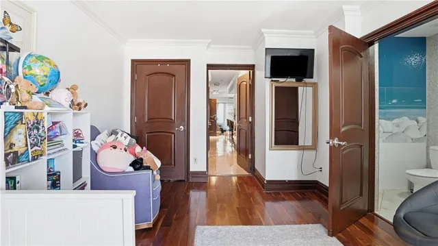 a bedroom with a bed wooden floor and a flat tv screen