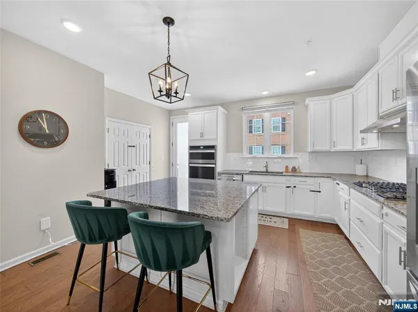 a kitchen with stainless steel appliances granite countertop a stove top oven a sink dishwasher a dining table and chairs with wooden floor