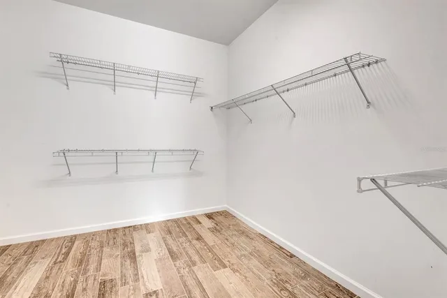 a view of an empty room with wooden floor and windows