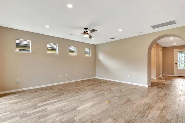 a view of an empty room with glass door and chandelier fan