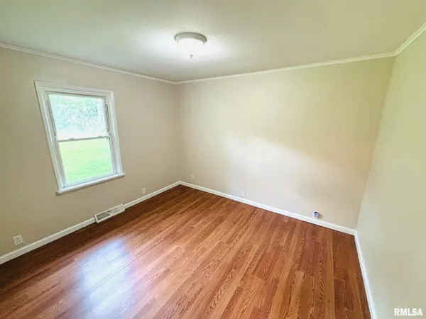 an empty room with wooden floor and entrance