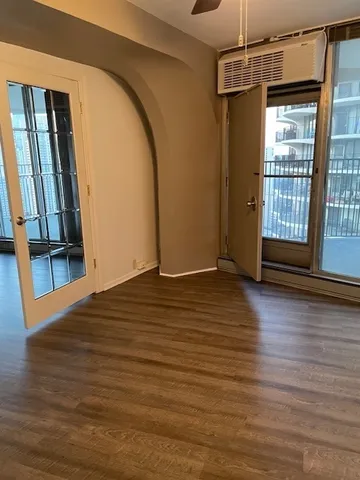 a view of empty room with wooden floor and fan