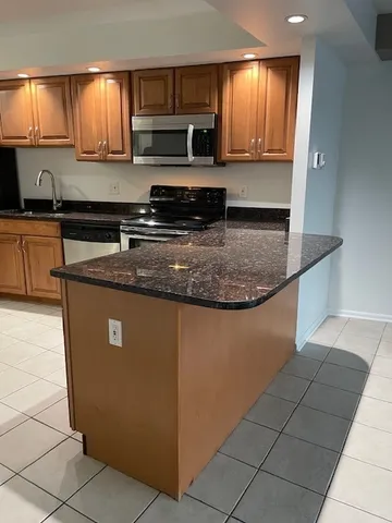 a kitchen with kitchen island granite countertop a sink a stove and cabinets