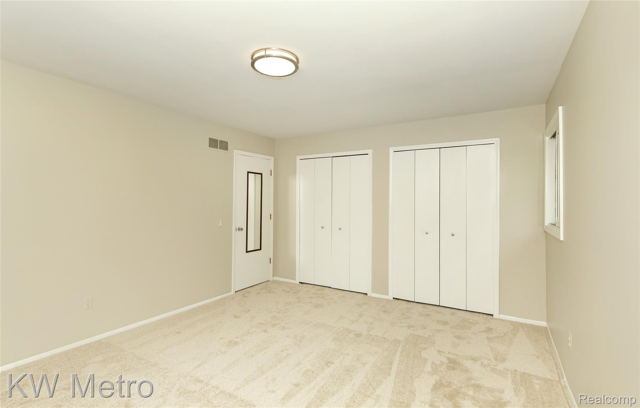 2154 Warrington Road Rochester, MI 48307 - Photo 26 of 41 Carpeted interior space featuring neutral wall tones, two sets of bi-fold closet doors, a door with a full-length mirror insert, a flush-mount ceiling light fixture, and a single window